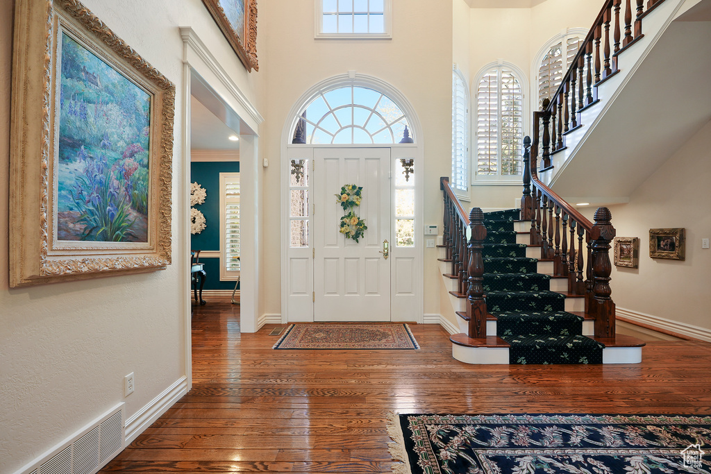 Foyer entrance featuring hardwood / wood-style floors, a towering ceiling, stairs, and baseboards