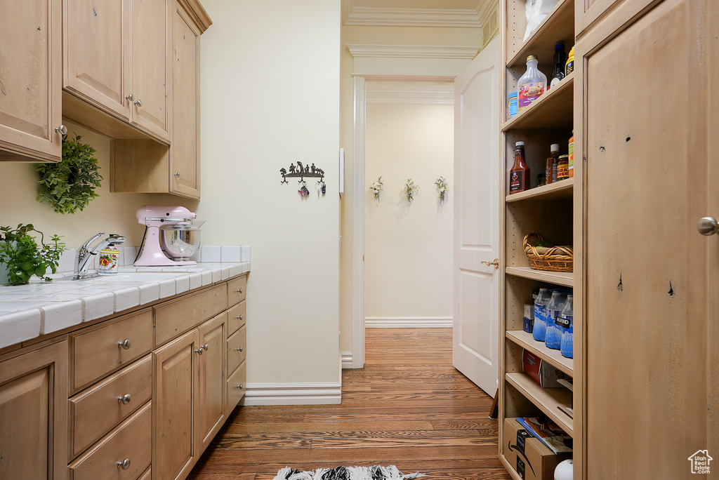 Kitchen featuring wood finished floors, tile counters, open shelves, and light brown cabinetry