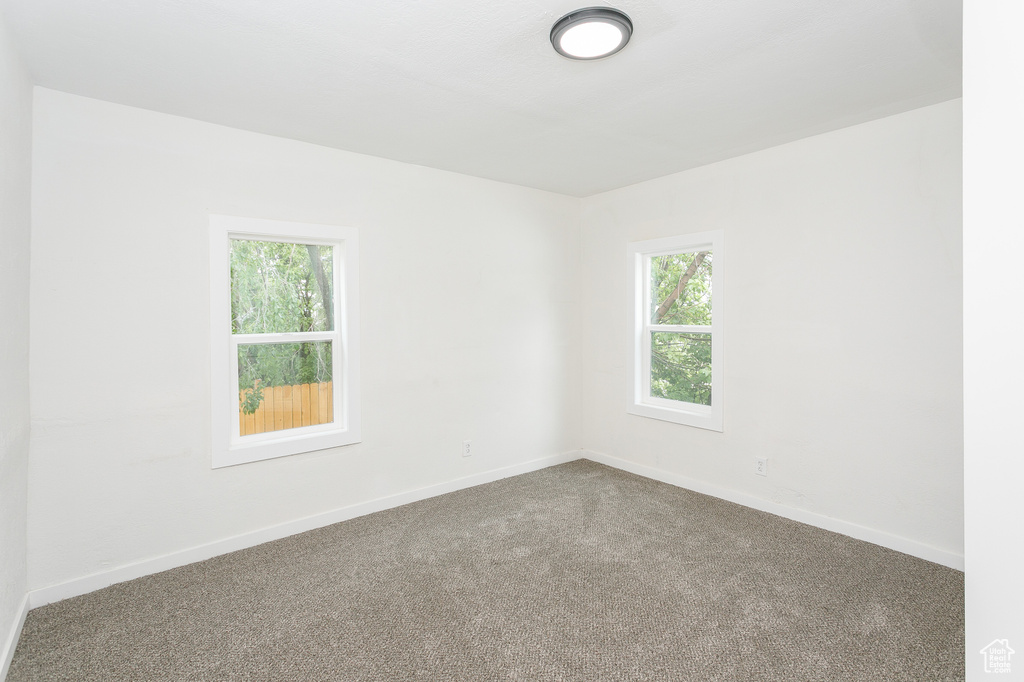 Spare room featuring healthy amount of natural light, carpet, and baseboards