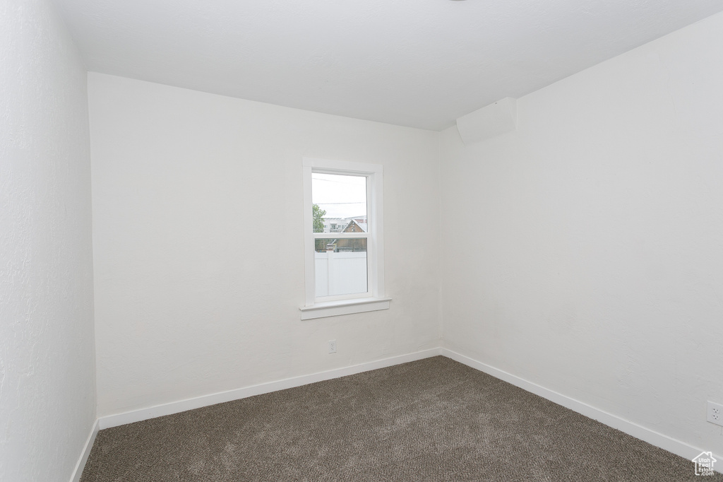 Spare room with dark colored carpet and baseboards