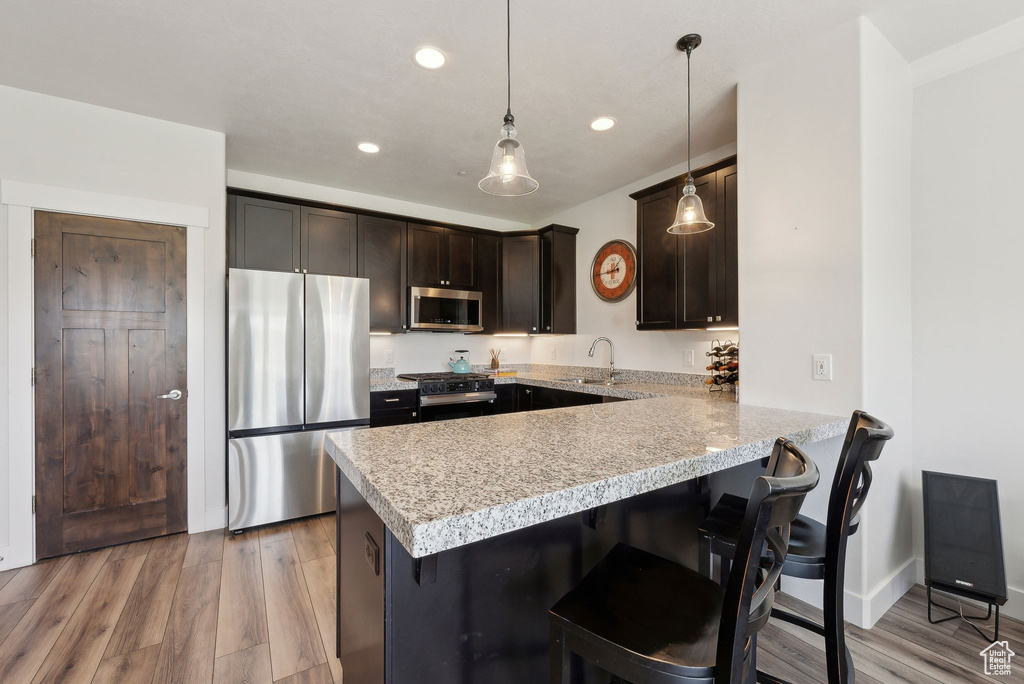 Kitchen with stainless steel appliances, a peninsula, light countertops, a breakfast bar area, and recessed lighting