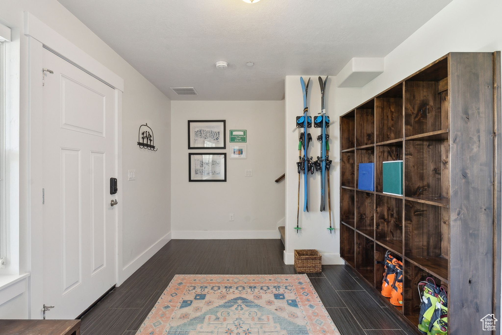 Foyer entrance with baseboards, dark wood-type flooring, and stairs