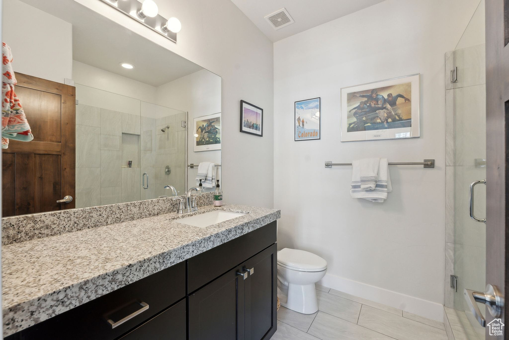 Full bath featuring toilet, vanity, a shower stall, baseboards, and tile patterned floors