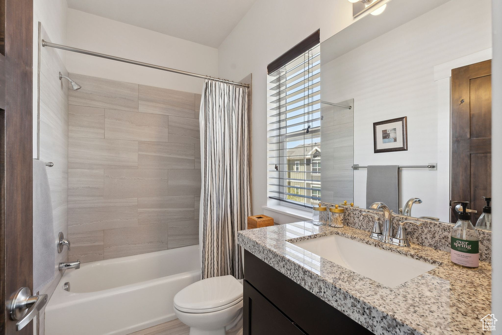 Bathroom featuring shower / bath combo with shower curtain, vanity, and toilet