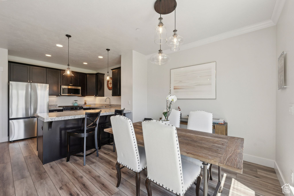 Dining room featuring recessed lighting, wood finished floors, baseboards, and crown molding