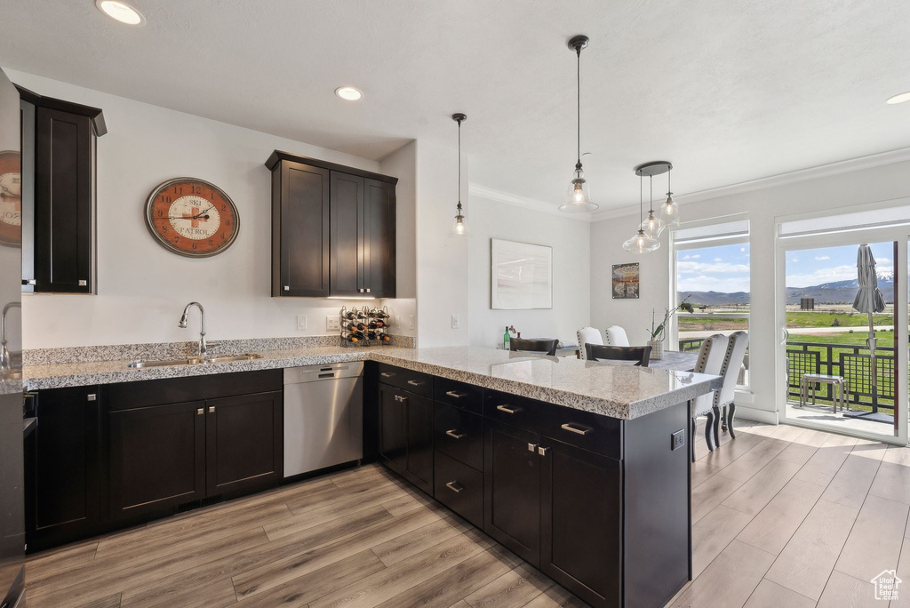 Kitchen featuring dishwasher, a sink, a peninsula, light wood-style floors, and crown molding
