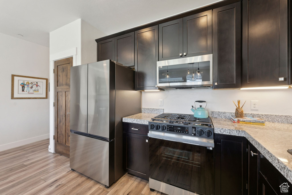 Kitchen featuring stainless steel appliances, light countertops, light wood-type flooring, baseboards, and dark brown cabinets