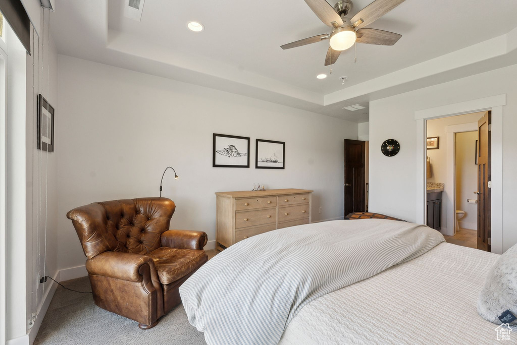 Bedroom with a raised ceiling, recessed lighting, baseboards, light carpet, and ensuite bathroom