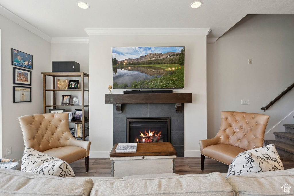 Living room featuring wood finished floors, a fireplace, recessed lighting, crown molding, and baseboards