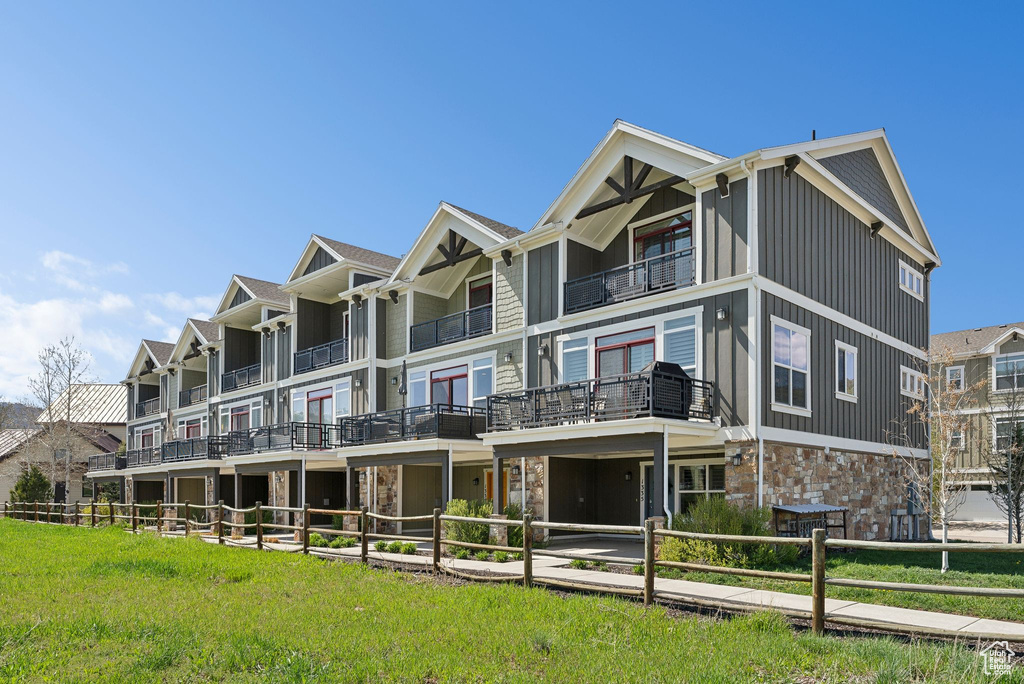 View of front of house with stone siding, a balcony, and board and batten siding