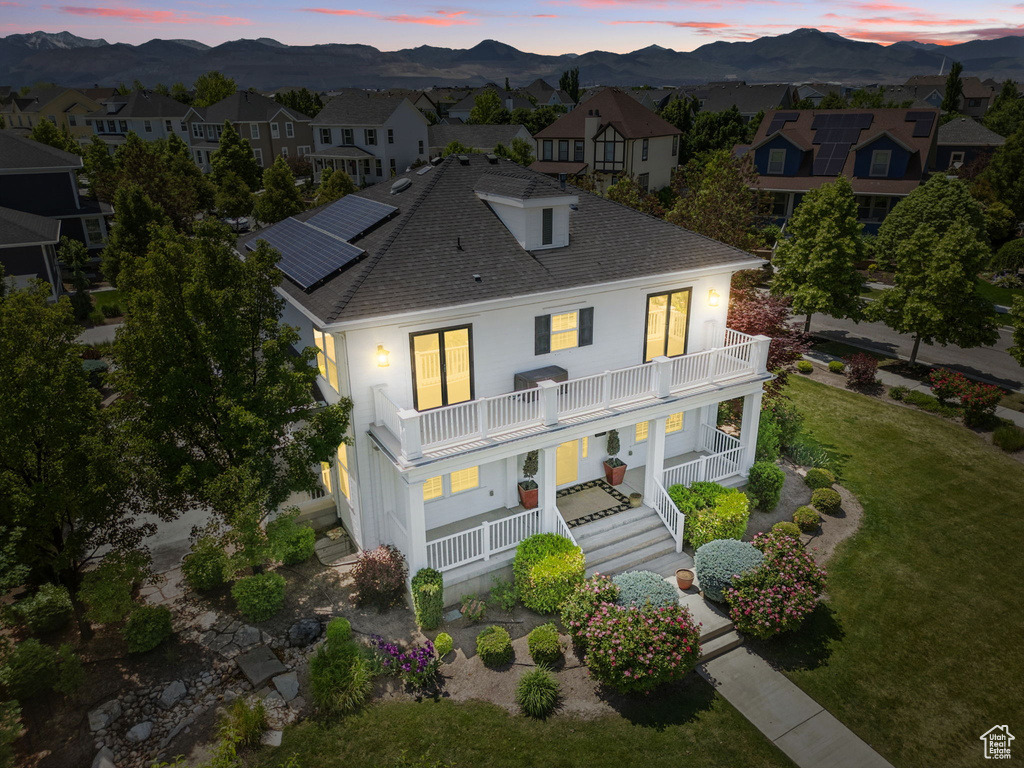 View of front of property with a balcony, a mountain view, covered porch, and roof with shingles