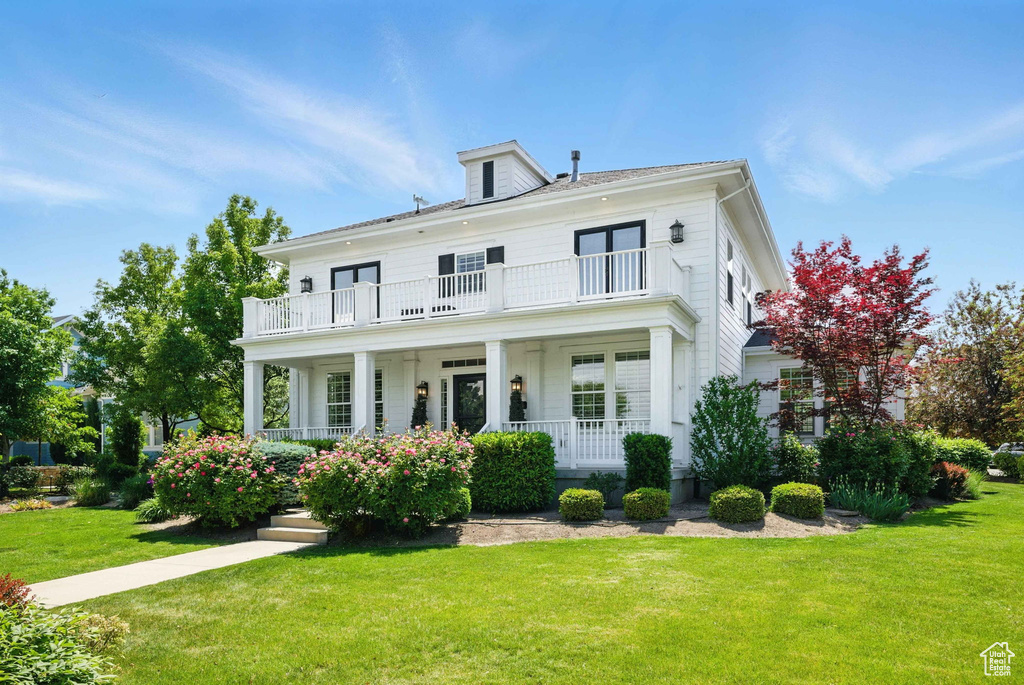 View of front of home featuring a balcony, a porch, and a front lawn