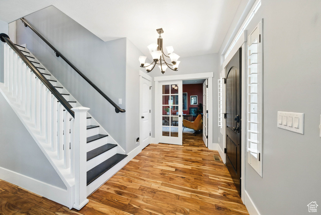 Entryway featuring a chandelier, wood finished floors, baseboards, and stairway