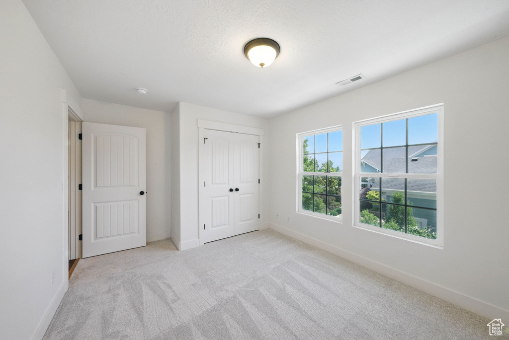 Unfurnished bedroom featuring carpet flooring, baseboards, and a closet