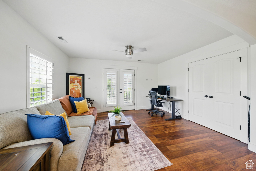 Living area featuring dark wood-style floors, arched walkways, ceiling fan, an office area, and french doors
