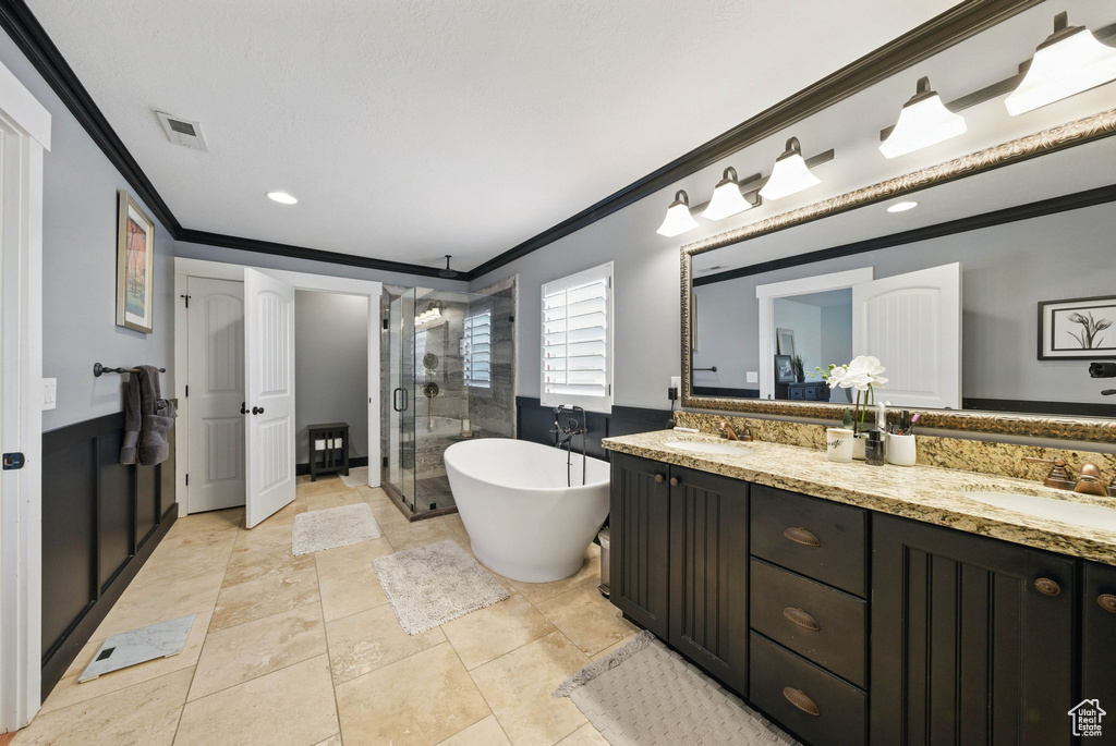 Bathroom featuring crown molding, a shower stall, double vanity, a freestanding tub, and recessed lighting