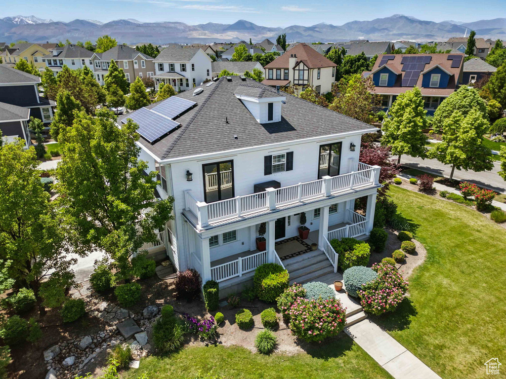 View of front of property with a balcony, a front lawn, a residential view, a mountain view, and roof with shingles