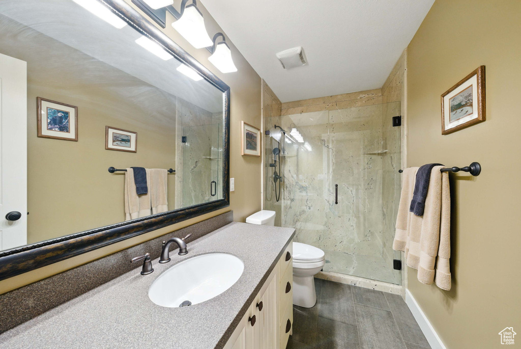 Full bath featuring toilet, a marble finish shower, vanity, and baseboards