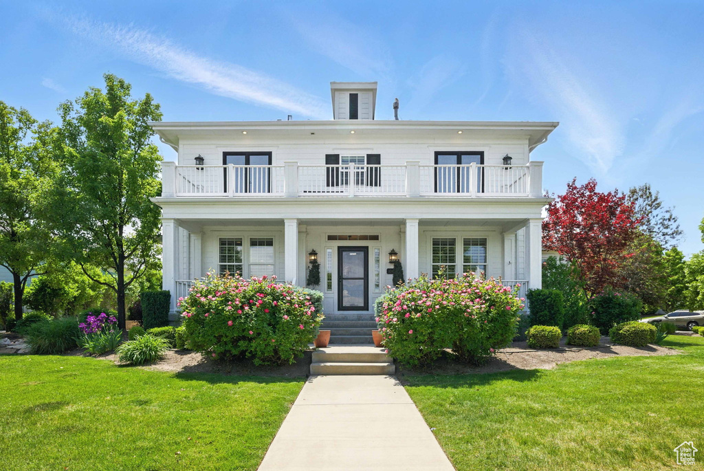 Greek revival house with a balcony, covered porch, and a front yard