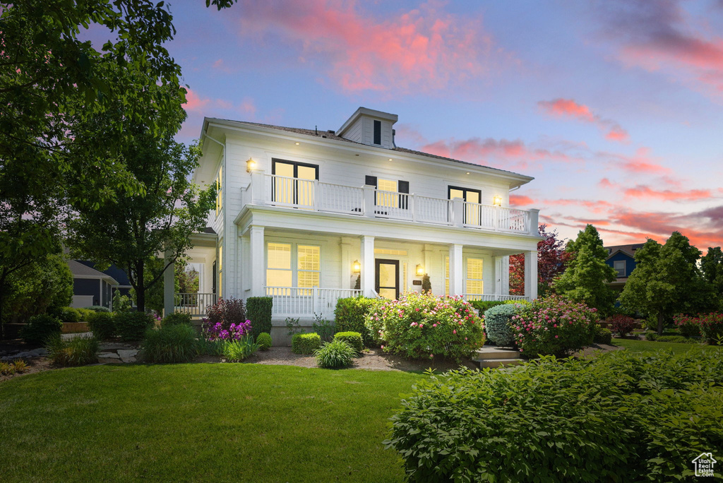 View of front of house with a balcony, a porch, and a front lawn