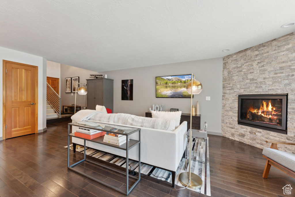 Living area with dark wood finished floors, stairway, a fireplace, and baseboards