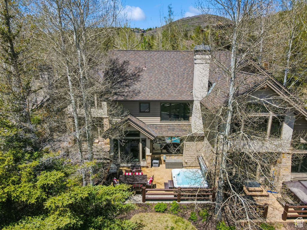 Back of house with an outdoor living space, a patio area, a chimney, and roof with shingles