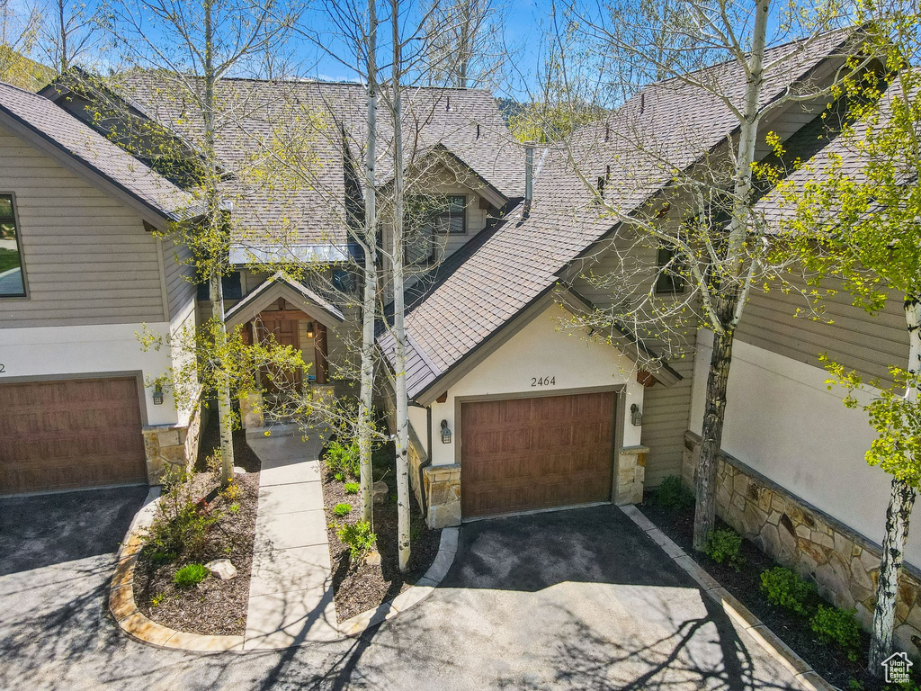 View of front of house with stone siding, driveway, and stucco siding