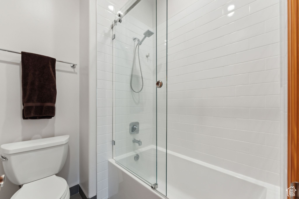 Bathroom featuring bath / shower combo with glass door and toilet