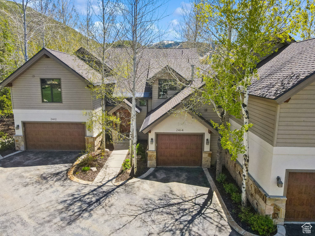 View of front of home featuring stone siding, driveway, and a garage
