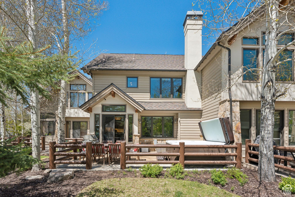 Back of property with a chimney and a shingled roof