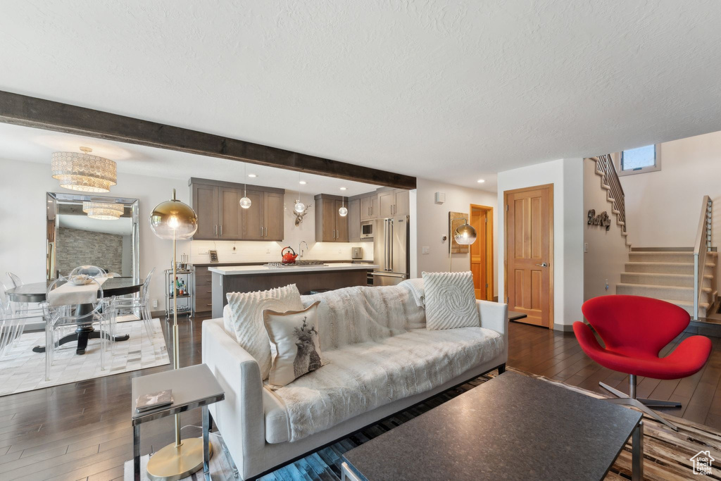 Living room featuring dark wood-type flooring, stairway, a textured ceiling, beam ceiling, and recessed lighting