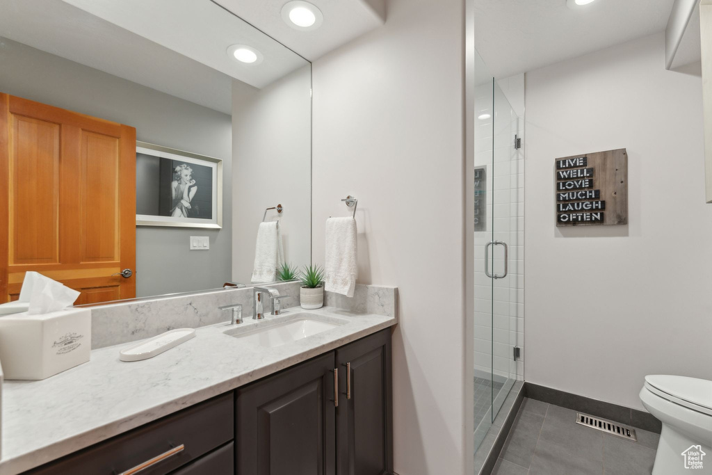 Full bath featuring vanity, tile patterned flooring, toilet, a stall shower, and baseboards