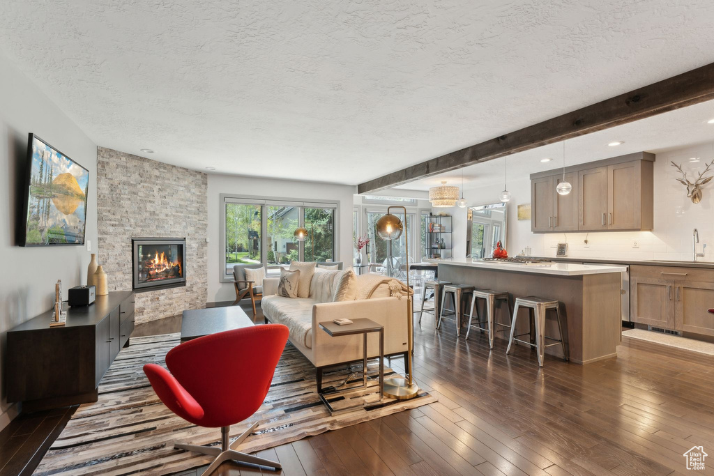 Living room featuring a textured ceiling, a fireplace, dark wood finished floors, and recessed lighting