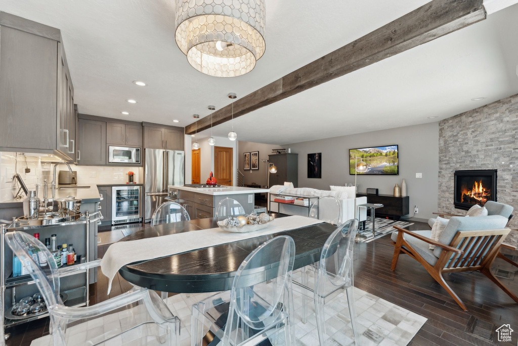 Dining space with wine cooler, dark wood-style flooring, a fireplace, beamed ceiling, and recessed lighting