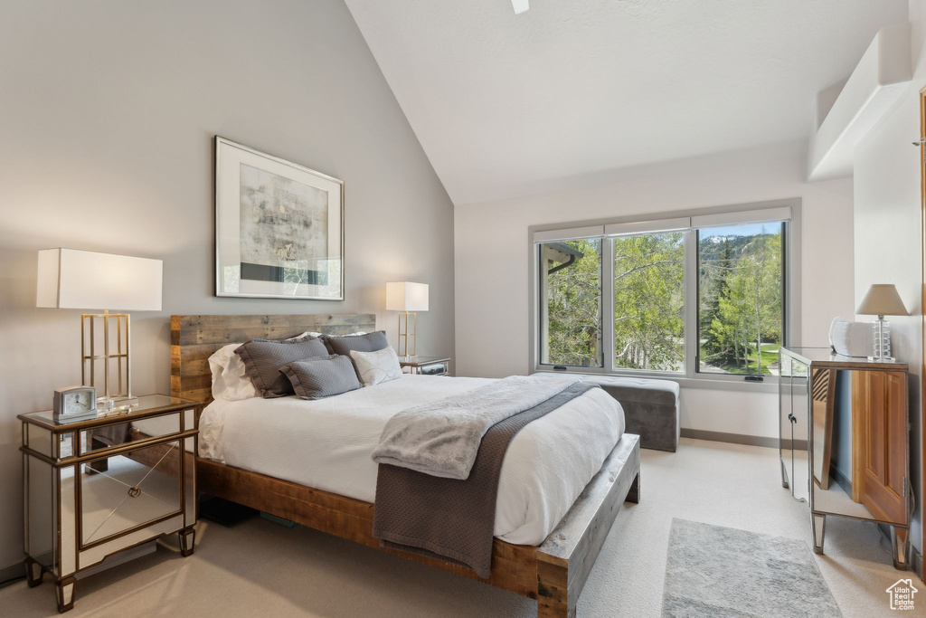 Bedroom with vaulted ceiling, light carpet, and baseboards