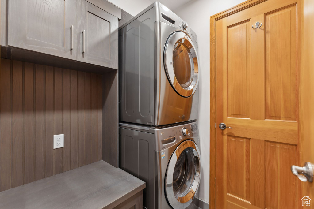 Washroom featuring stacked washer and clothes dryer and cabinet space