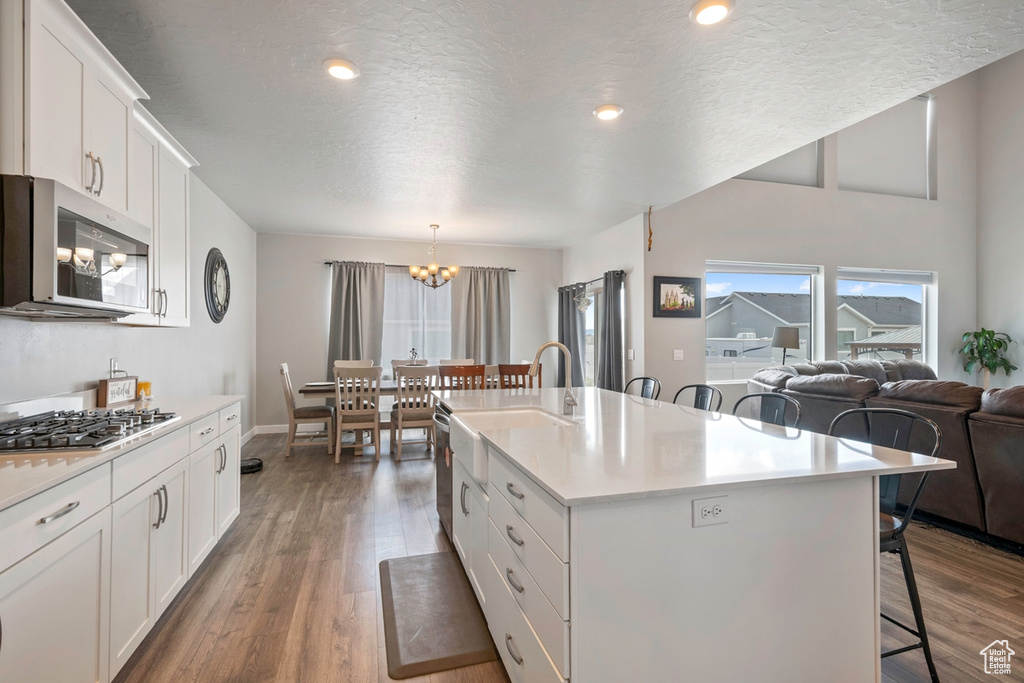 Kitchen with appliances with stainless steel finishes, a kitchen breakfast bar, a chandelier, healthy amount of natural light, and a textured ceiling