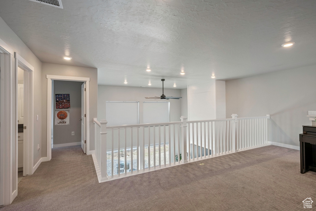 Hall with carpet, recessed lighting, baseboards, a textured ceiling, and an upstairs landing