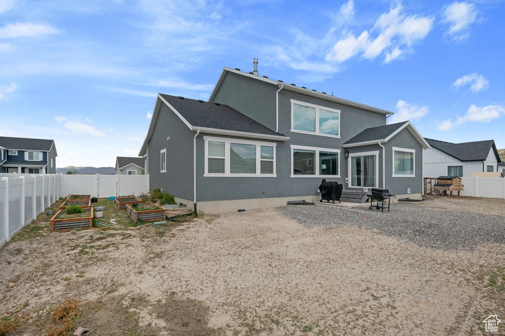Rear view of property featuring a vegetable garden, entry steps, and stucco siding