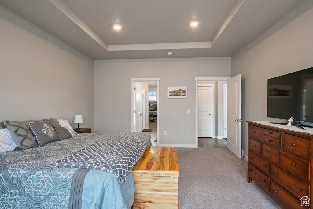 Bedroom with a tray ceiling, recessed lighting, baseboards, and light wood-style flooring
