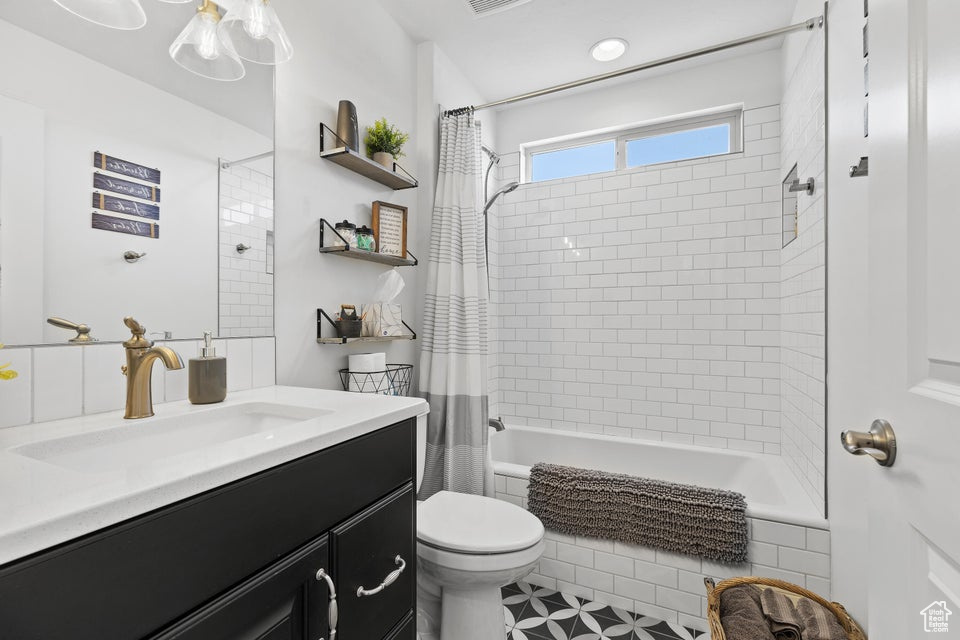Bathroom with tiled shower / bath, vanity, and toilet