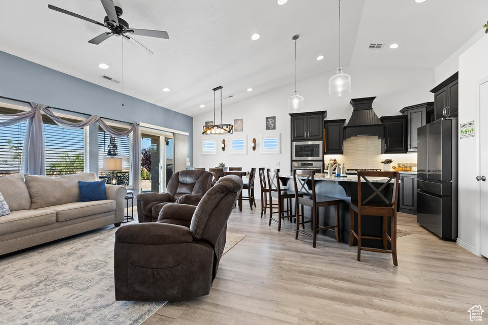 Living area featuring a ceiling fan, light wood-style floors, recessed lighting, and high vaulted ceiling