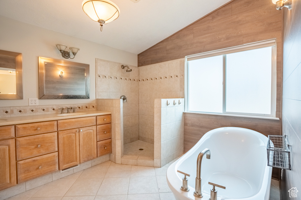 Full bath with vaulted ceiling, tiled shower, a bath, vanity, and tile patterned flooring