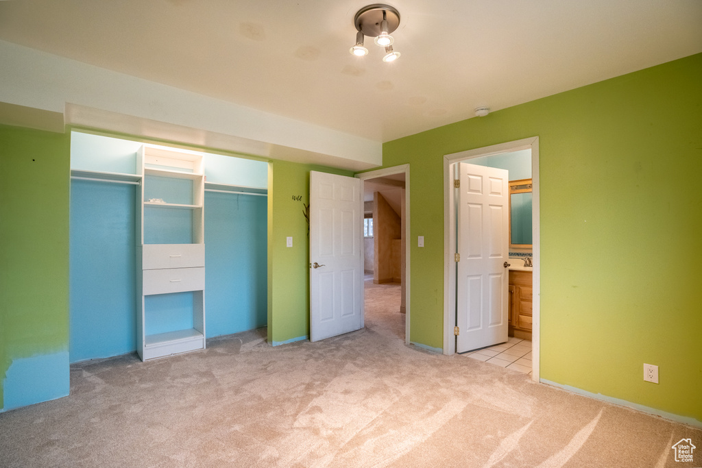 Unfurnished bedroom with carpet floors, a closet, ensuite bathroom, and baseboards