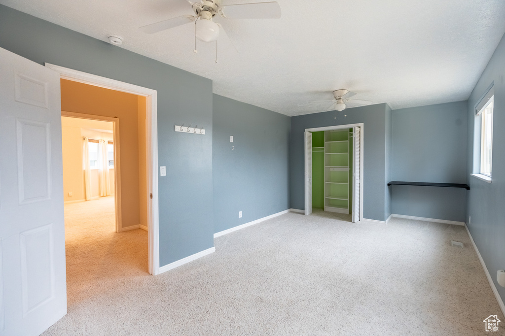 Carpeted empty room with ceiling fan, a smoke detector, and baseboards