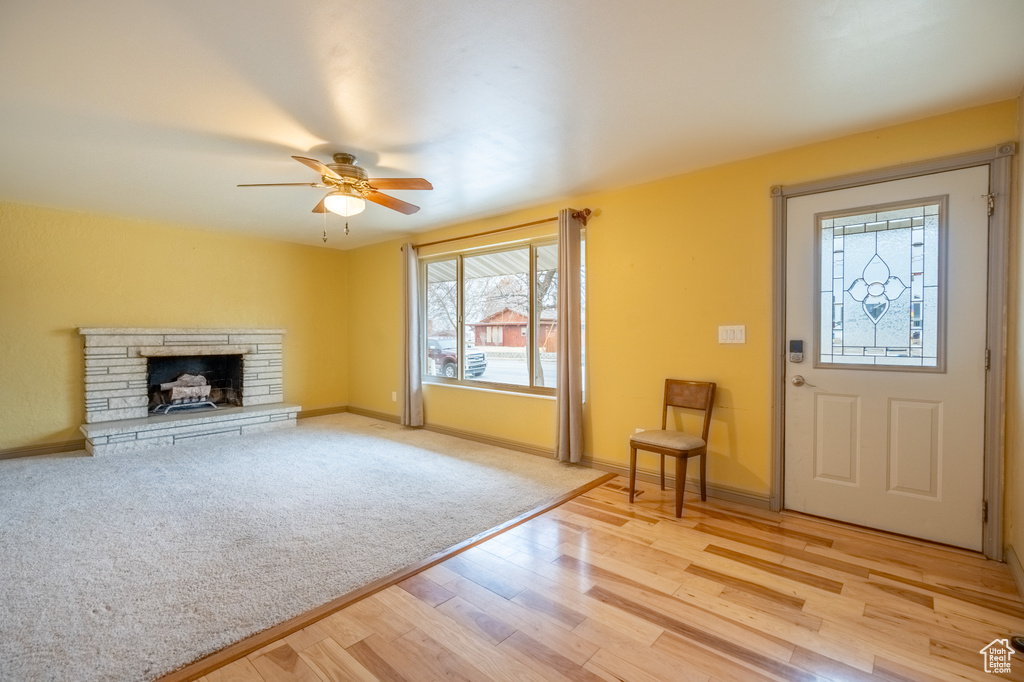 Unfurnished living room with light wood-style floors, ceiling fan, a fireplace, and baseboards