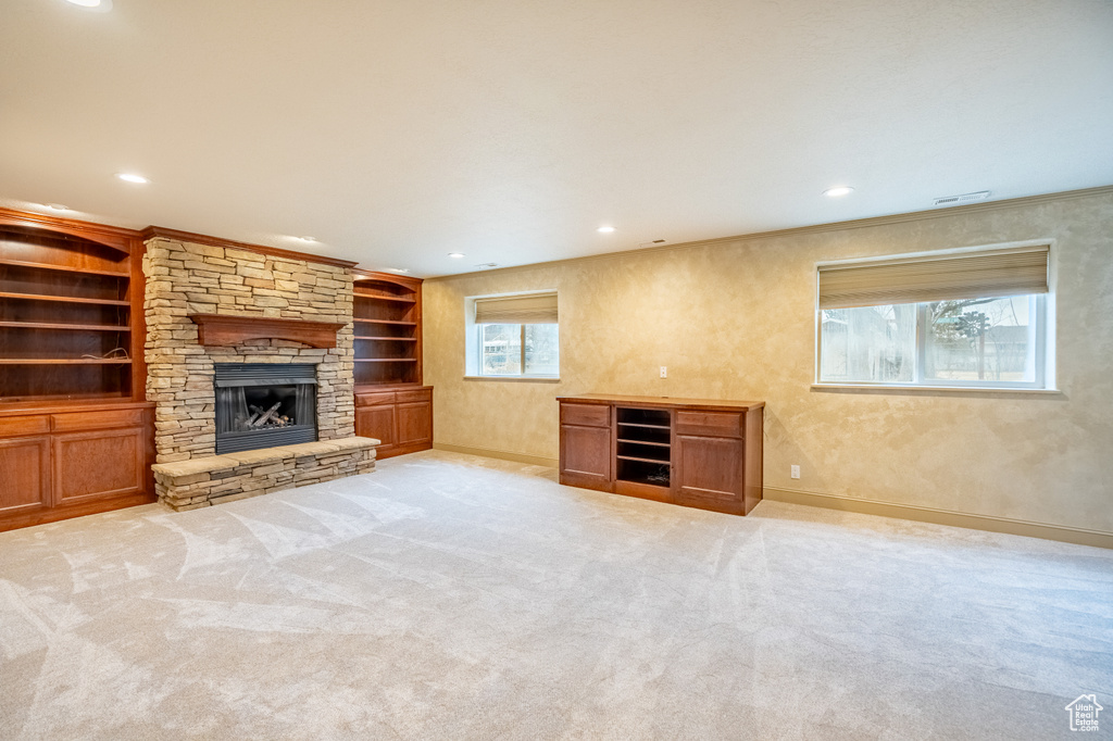 Unfurnished living room with a stone fireplace, carpet, recessed lighting, baseboards, and built in features