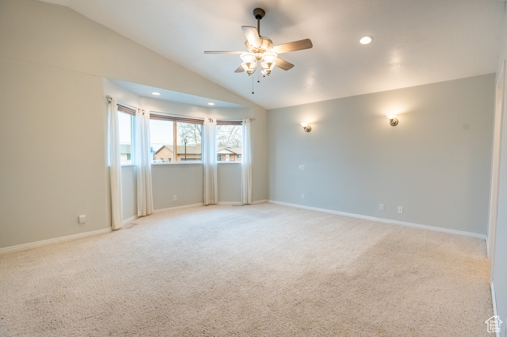 Empty room featuring a ceiling fan, vaulted ceiling, light carpet, recessed lighting, and baseboards