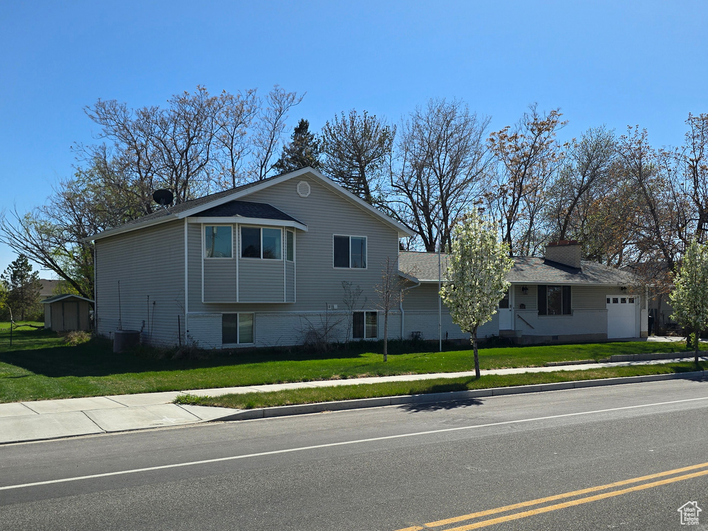 View of front facade featuring a front yard, a garage, and central AC