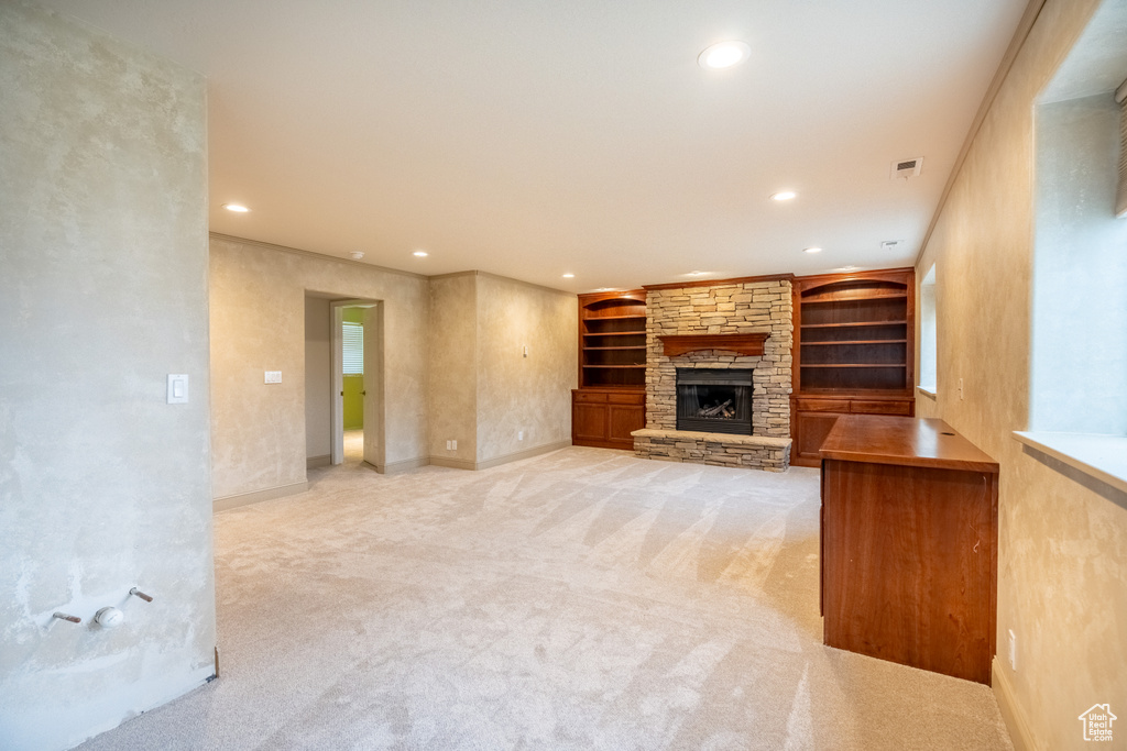 Unfurnished living room featuring recessed lighting, a stone fireplace, light carpet, built in features, and baseboards